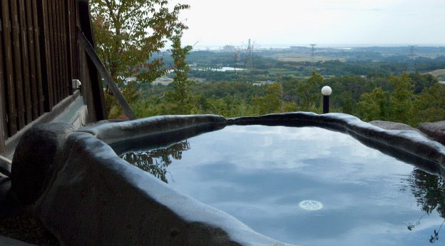 鹿狼の湯の露天風呂。湯面の向こうに新地町の景色が見える